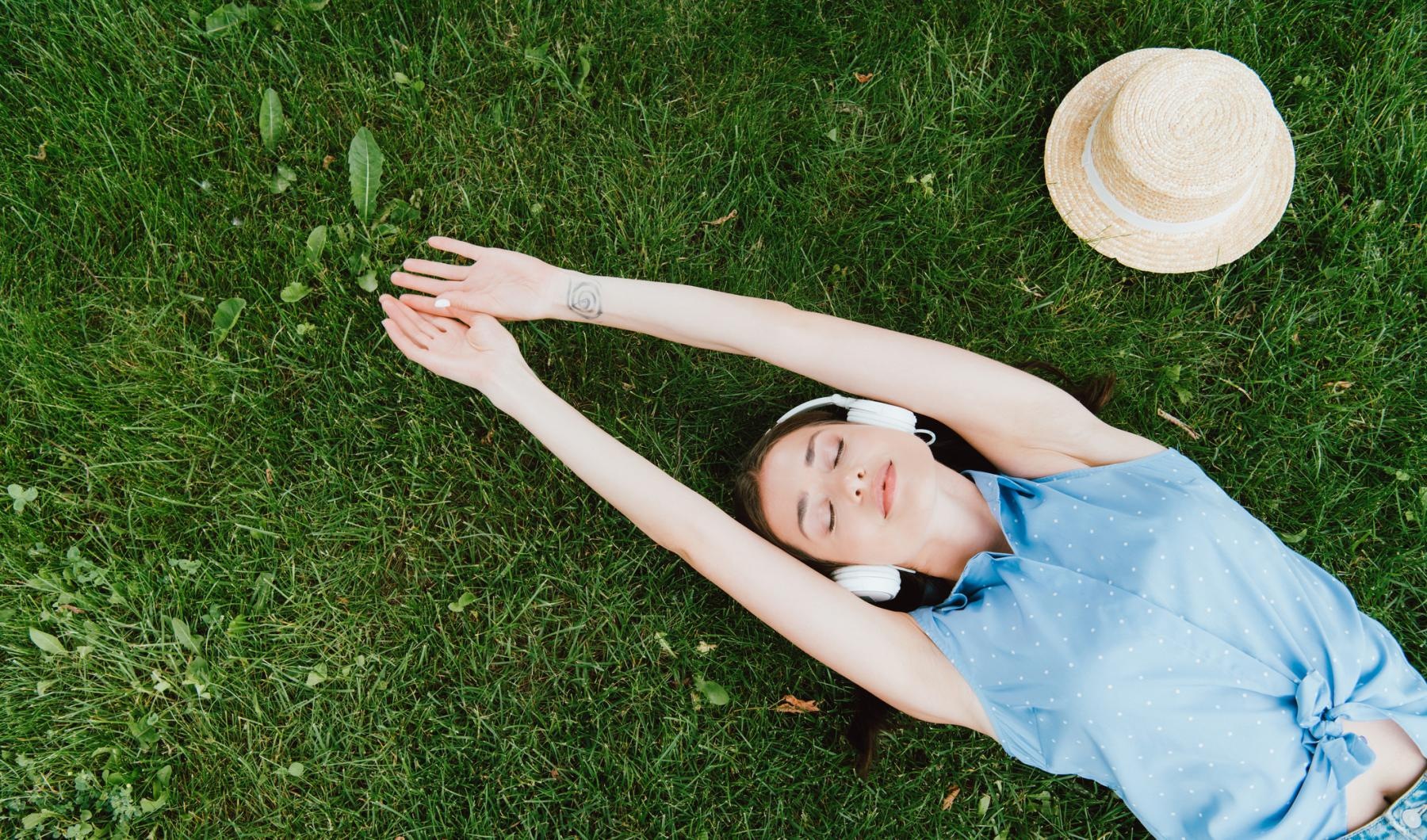 a person lying in the grass listening to music