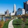 a park with walkway river next to a downtown area
